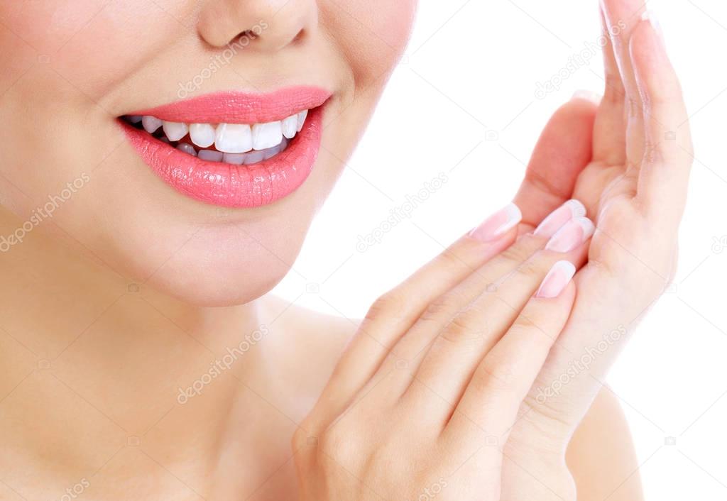Closeup shot of beautiful female smile and manicured fingers, white background.