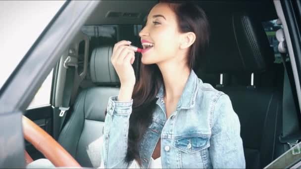 Young woman sitting in a car doing makeup — Stock Video