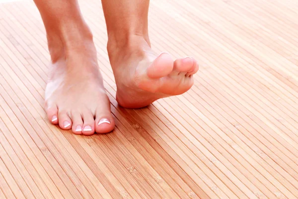Vrouwelijke voeten op een bamboe mat. — Stockfoto