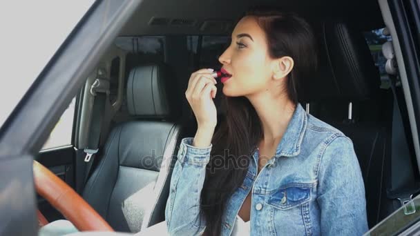 Jovem mulher sentada em um carro fazendo maquiagem — Vídeo de Stock