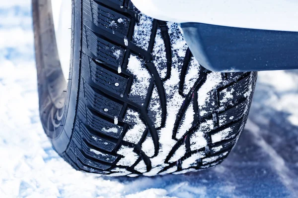 Closeup shot of automobile studded tire covered with snow at winter snowy road — Stock Photo, Image