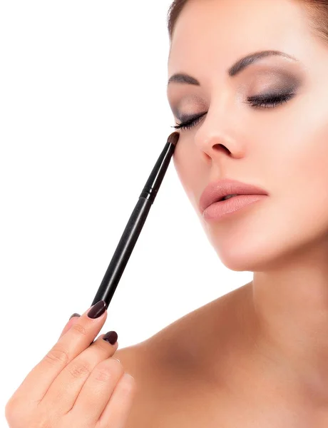 Vacker kvinna håller makeup borste, isolerad på vit bakgrund — Stockfoto
