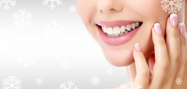 Närbild skott av kvinnans toothy leende mot en grå bakgrund med snöflingor — Stockfoto