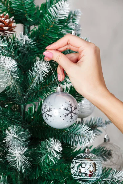 La mano de la mujer colgando bola de Navidad de plata en el abeto, concepto de vacaciones — Foto de Stock