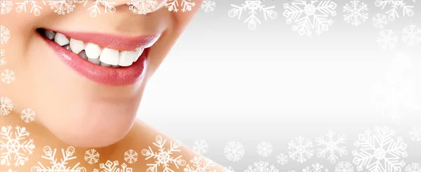 Pretty woman smiling against a grey background with copyspace and snowflakes. Christmas time concept — Stock Photo, Image