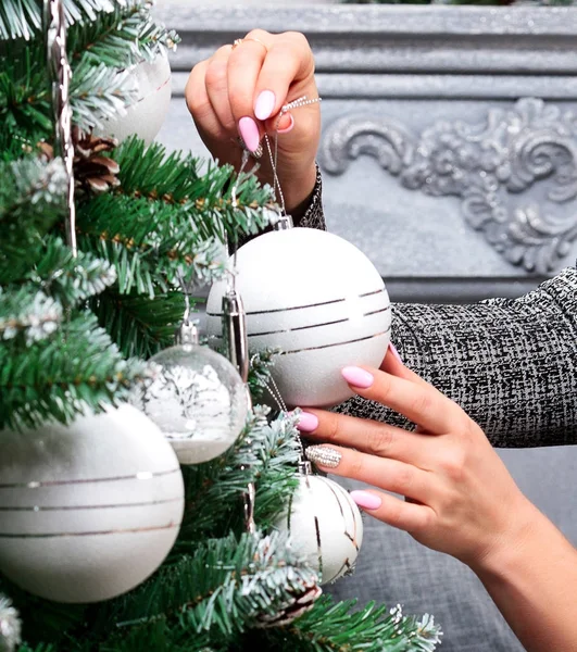 Mãos de mulher pendurado bola de Natal de prata no abeto, conceito de férias — Fotografia de Stock