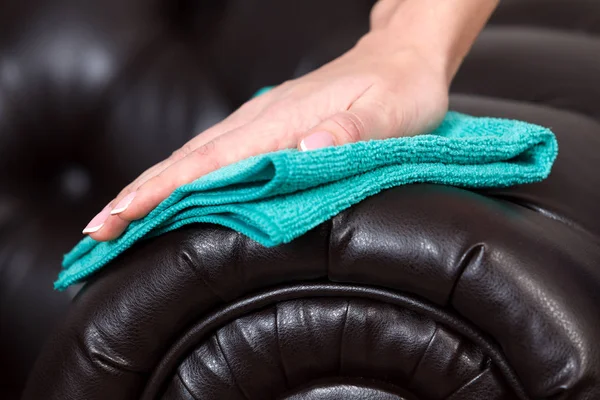 Primer plano de mano femenina limpiando sofá de cuero marrón de sofá — Foto de Stock