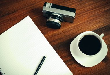 Retro film fotoğraf makinesi, fincan kahve ve defter kalem kahverengi tablosundaki ile. Üstten Görünüm.