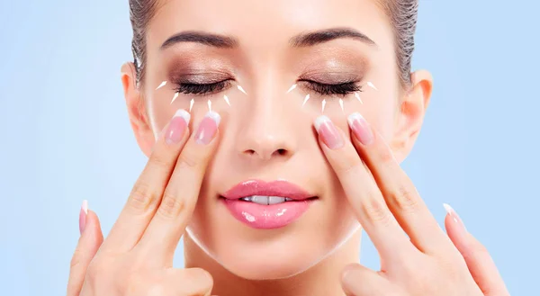 Primo piano di giovane donna di bellezza massaggiare il viso. Il concetto di massaggio facciale. Isolato su sfondo azzurro — Foto Stock