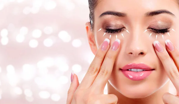 Ładna kobieta masuje jej twarz, koncepcję antiaging leczenia skóry. Tło z niewyraźne lights — Zdjęcie stockowe