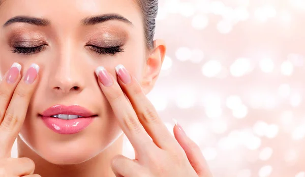 Mulher bonita a massajar o rosto, conceito de tratamento de pele. Fundo abstrato com luzes embaçadas — Fotografia de Stock
