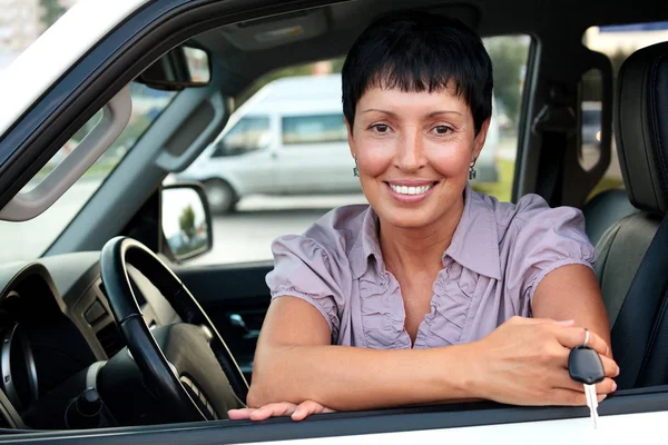 Senior mulher motorista de carro segurando uma chave e sorrindo para você — Fotografia de Stock