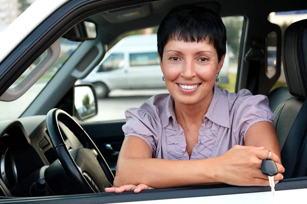 Autista senior donna in possesso di una chiave e sorridente a voi — Foto Stock