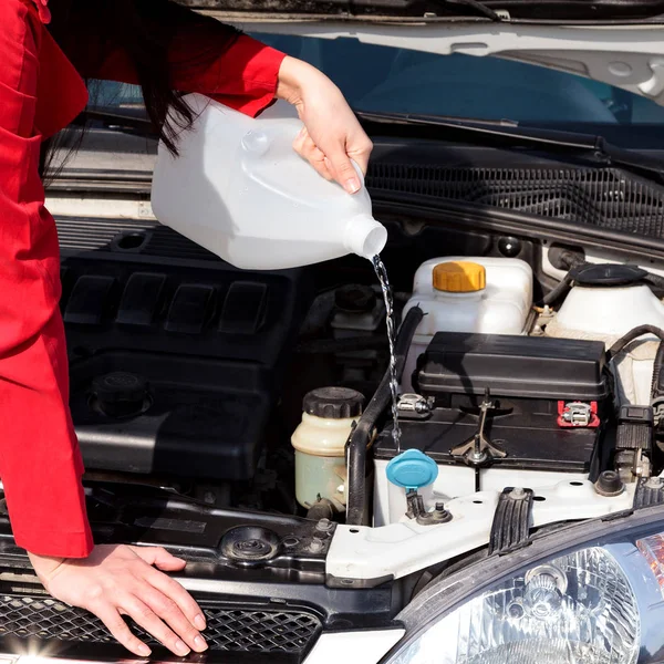 Abgeschnittenes Bild einer Frau, die Scheibenwaschflüssigkeit ins Auto schüttet — Stockfoto