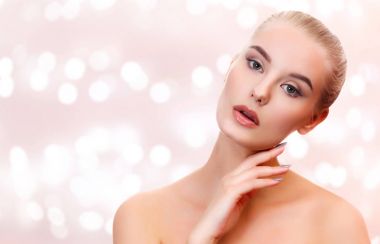 Pürüzsüz ve yumuşak, güzel genç kadın bir bstract arka plan bulanık ışıkları ile karşı cildi temizlemek