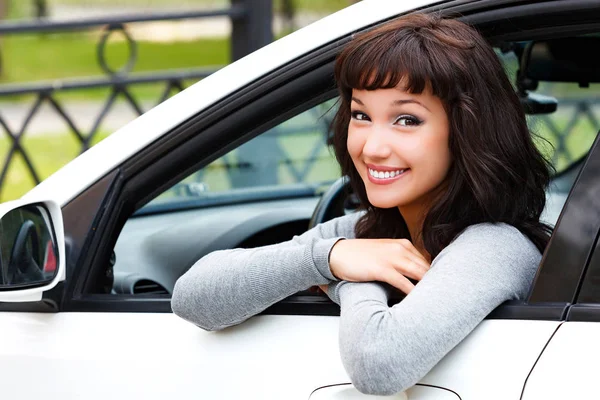 Mujer bonita conductor sonriendo a usted desde el coche blanco — Foto de Stock