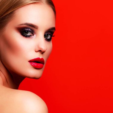Kırmızı bir arka plan karşı poz parlak kalıcı makyaj ile güzel bir kadın portresi portre