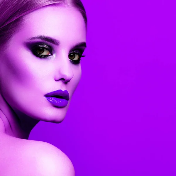 Nahaufnahme Porträt einer schönen Frau mit hellem Make-up, die vor violettem Hintergrund posiert — Stockfoto