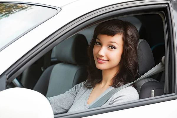 Гарненька жінка водій посміхається тобі з білої машини — стокове фото