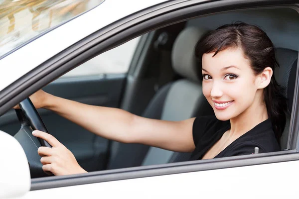 Mujer bonita conductor sonriendo a usted desde el coche blanco — Foto de Stock