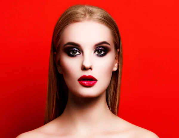 Retrato de cerca de una mujer hermosa con maquillaje brillante posando sobre un fondo rojo —  Fotos de Stock