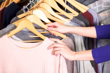 Kim yeni giysiler seçmek moda kadın elinde kadeh closeup kavramı alışveriş