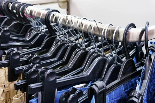 Closeup shot of row of pants and jeans on the hangers in modern clothing store — Stock Photo, Image