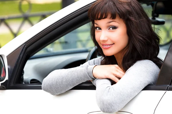 Lycklig ägare till en ny bil. Ung vacker kvinna driver leende till dig — Stockfoto