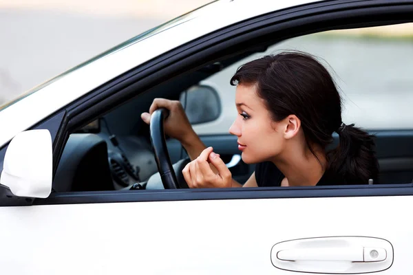 Lindo conductor femenino mirando en un espejo retrovisor — Foto de Stock