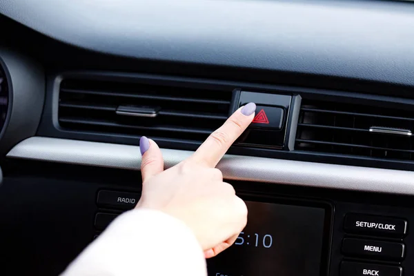 Closeup shot of woman's manicured finger pressing the emergency button on a car's dashboard — Stock Photo, Image