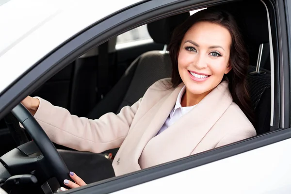 Lycklig ägare till en ny bil. Leende ung vacker kvinna som sitter i hennes bil — Stockfoto