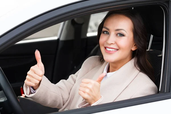 Mujer hermosa conductor sonriendo y dando pulgar hacia arriba dentro de su coche — Foto de Stock