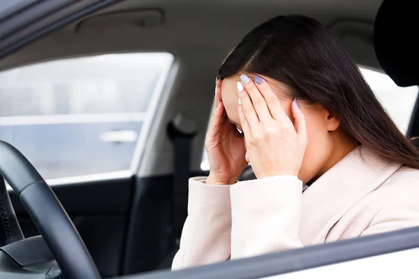 Молода пригнічена жінка водій тримає голову в руках — стокове фото