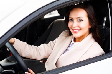 Yeni bir araba mutlu sahibi. Onun otomobil içinde oturan genç gülümseyen güzel kadın