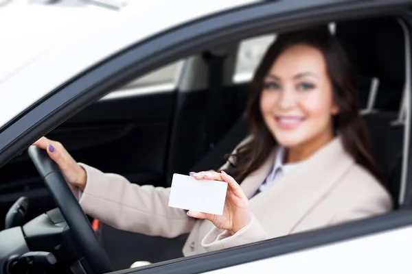 白い空白の名刺を保持する女性ドライバーを笑顔の肖像画。白いカードにフォーカスがあります。 — ストック写真