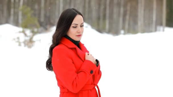 Happy young woman in red coat posing in winter forest and sending you a kiss — Stock Video