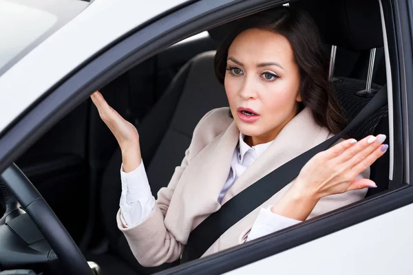 Young pretty woman driver driving a car and arguing with someone — Stock Photo, Image