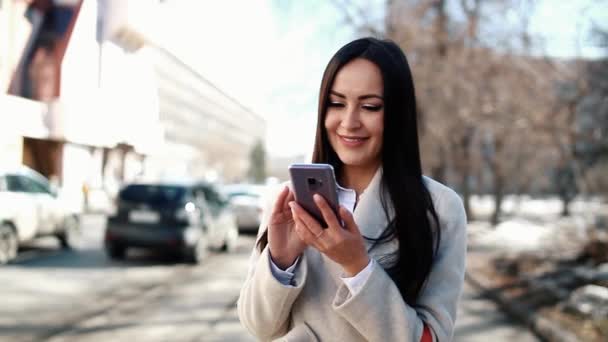 Vacker kvinna med hennes smartphone utomhus — Stockvideo