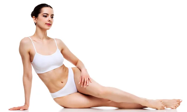 Benessere e concetto di bellezza, bella donna magra in biancheria intima bianca seduta sul pavimento bianco — Foto Stock