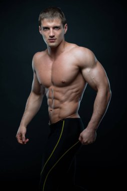 Spor tişörtsüz erkek model kaslarını esnetiyor.