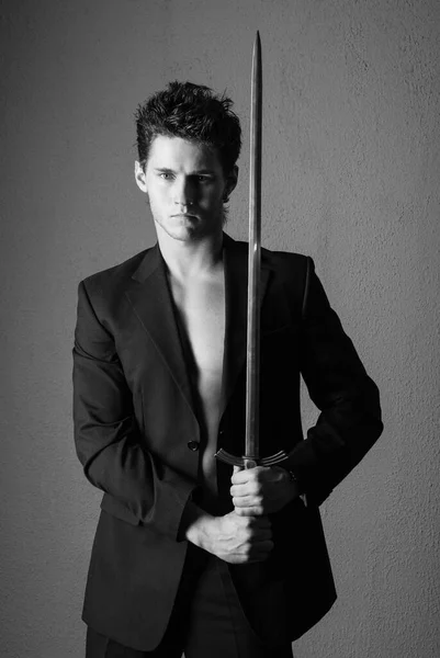 Young good-looking model in suite with a sword