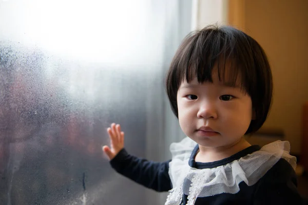 Pequeño niño parado junto a la ventana — Foto de Stock