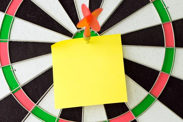 Blank sticky note on dartboard with dart — Stock Photo, Image