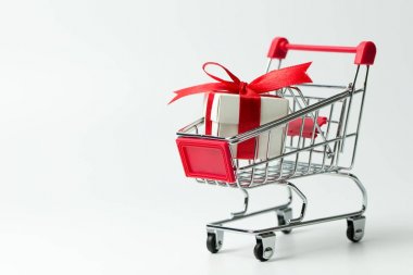 Bir alışveriş sepeti içinde kırmızı kurdele ile bağlanmış beyaz hediye kutusu