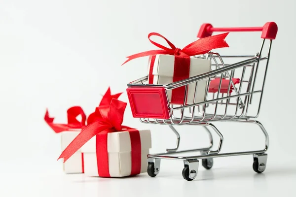 Caja de regalo blanca atada con cinta roja en un carrito de compras —  Fotos de Stock