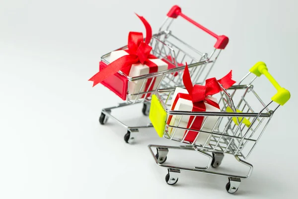 Caja de regalo blanca atada con cinta roja en dos carritos de compras —  Fotos de Stock