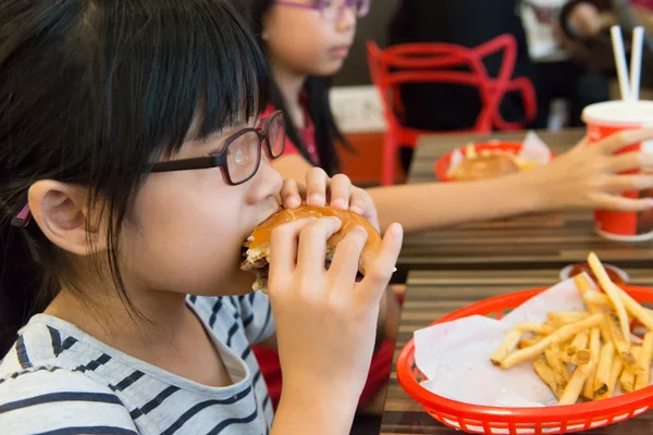 ハンバーガーとフライド ポテトを食べるアジアの子供 — ストック写真