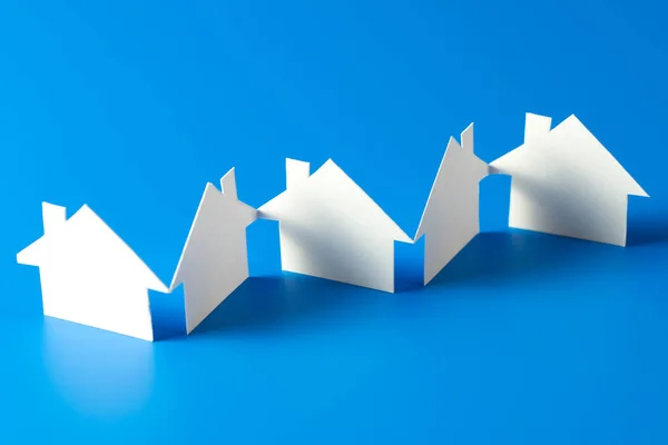 Huis gesneden uit papier op blauwe achtergrond — Stockfoto