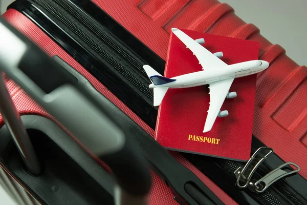 Czerwony paszport i samolot model na czerwony bagażu — Zdjęcie stockowe