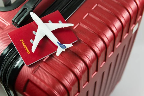 Pasaporte rojo y modelo de avión en equipaje rojo — Foto de Stock